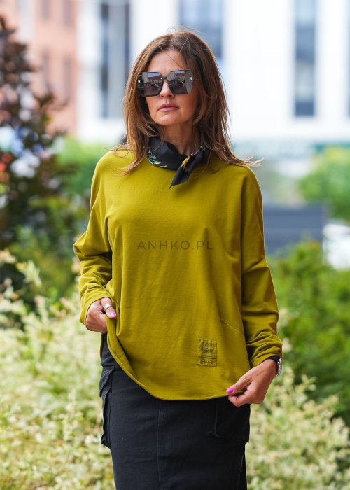 Oliwkowa bawełniana bluza damska Nora o bardzo luźnym kroju oversize z wydłużonym tyłem i dekoracyjną naszywką przy dolnej krawędzi.