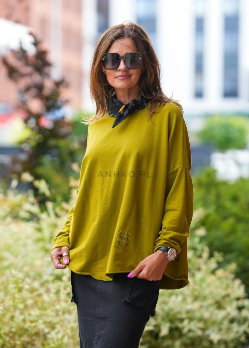 Oliwkowa bawełniana bluza damska Nora o bardzo luźnym kroju oversize z wydłużonym tyłem i dekoracyjną naszywką przy dolnej krawędzi.