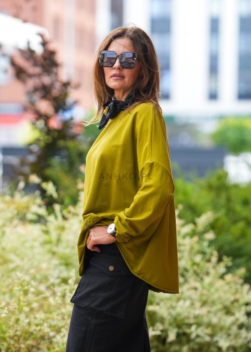 Oliwkowa bawełniana bluza damska Nora o bardzo luźnym kroju oversize z wydłużonym tyłem i dekoracyjną naszywką przy dolnej krawędzi.