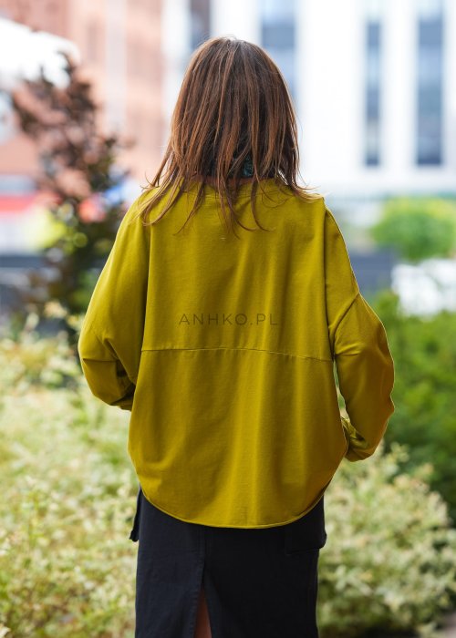 Oliwkowa bawełniana bluza damska Nora o bardzo luźnym kroju oversize z wydłużonym tyłem i dekoracyjną naszywką przy dolnej krawędzi.