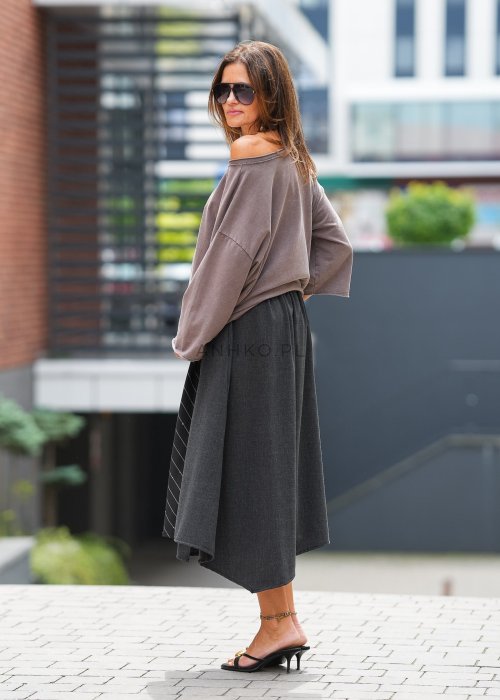 Brązowa bluzka oversize damska z szerokim dekoltem i haftowanym motywem kwiatowym na rękawie. Stylizacja z szerokimi spodniami w miejskim klimacie.
