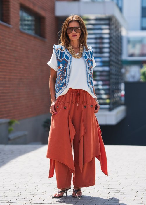 Niebieska kamizelka jeansowa damska z bogatymi haftami i surowym wykończeniem. Stylizacja z beżową sukienką i biżuterią w stylu boho.