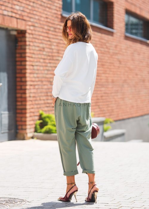 Zielone spodnie damskie oversize z dużymi kieszeniami i elastycznym pasem. Stylizacja z jasną bluzką i eleganckimi szpilkami w miejskim stylu.