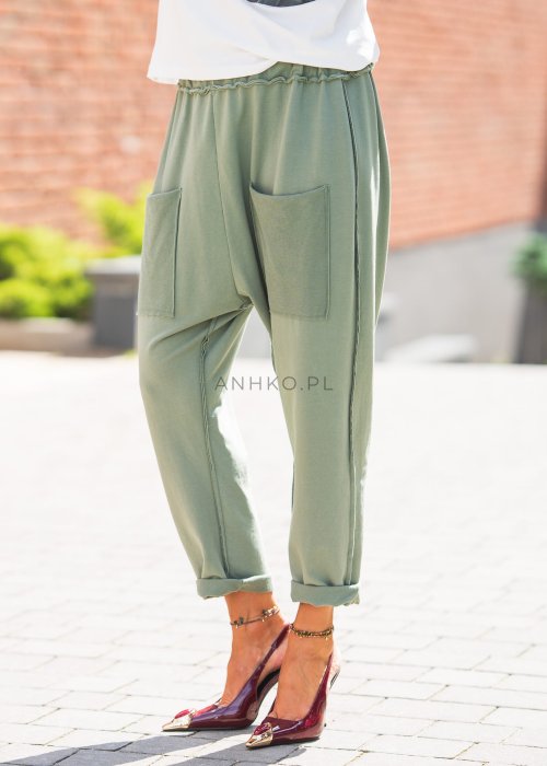 Zielone spodnie damskie oversize z dużymi kieszeniami i elastycznym pasem. Stylizacja z jasną bluzką i eleganckimi szpilkami w miejskim stylu.