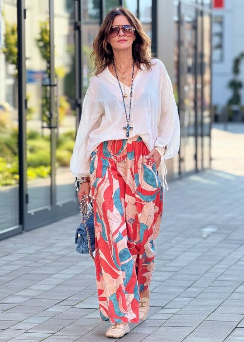 Szerokie spodnie damskie palazzo z wysokim stanem, wzór w duże kwiaty w odcieniach czerwieni, beżu i turkusu, styl boho