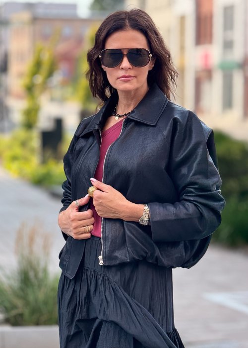 Czarna krótka kurtka damska z długim rękawem i kołnierzem, wykonana ze skóry ekologicznej, styl minimalistyczny