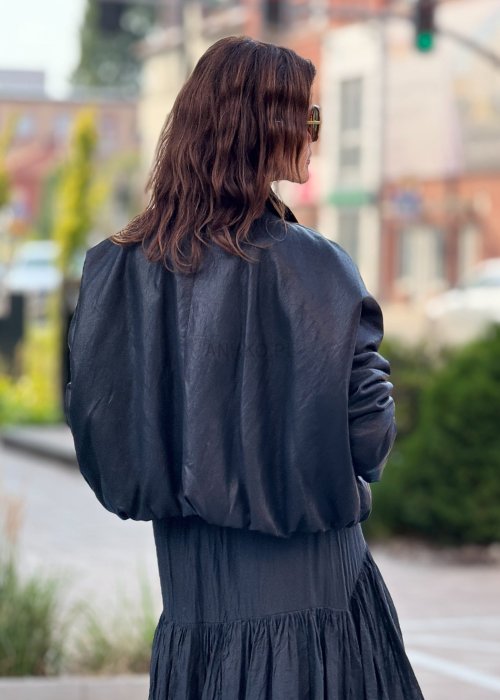 Czarna krótka kurtka damska z długim rękawem i kołnierzem, wykonana ze skóry ekologicznej, styl minimalistyczny