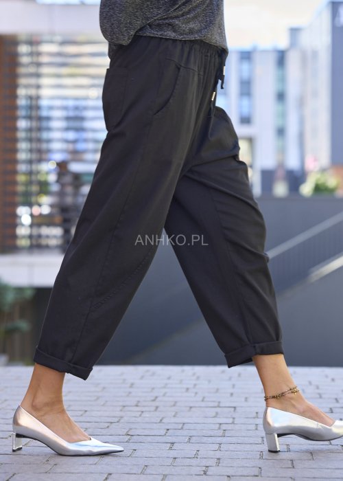 Czarne spodnie damskie RelaxFit z elastycznym pasem i podwiniętymi nogawkami, stylizowane z luźną bluzką i srebrnymi szpilkami w miejskim looku.
