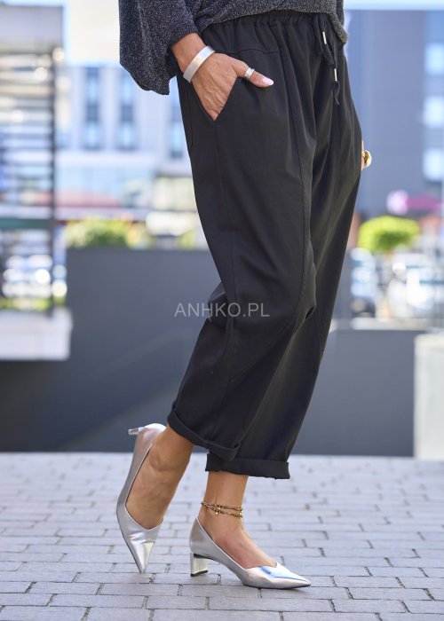 Czarne spodnie damskie RelaxFit z elastycznym pasem i podwiniętymi nogawkami, stylizowane z luźną bluzką i srebrnymi szpilkami w miejskim looku.