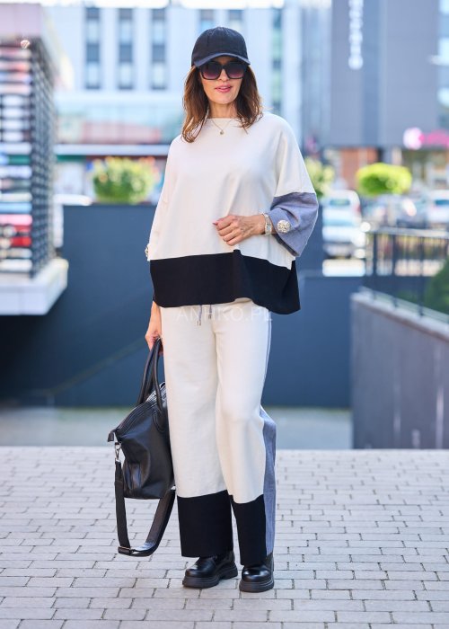 Damski komplet w stylu casual – oversizowa bluzka z szerokimi rękawami w kolorze biało–szaro–czarnym, ozdobiona broszkami przy mankietach, zestawiona z dopasowanymi spodniami w tej samej kolorystyce
