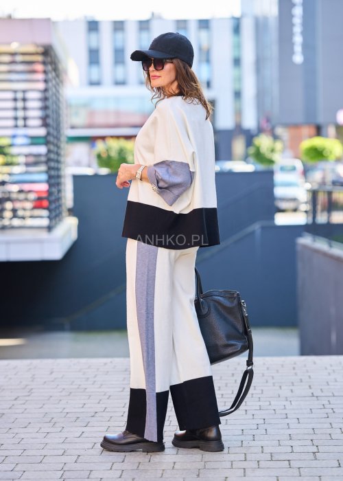 Damski komplet w stylu casual – oversizowa bluzka z szerokimi rękawami w kolorze biało–szaro–czarnym, ozdobiona broszkami przy mankietach, zestawiona z dopasowanymi spodniami w tej samej kolorystyce