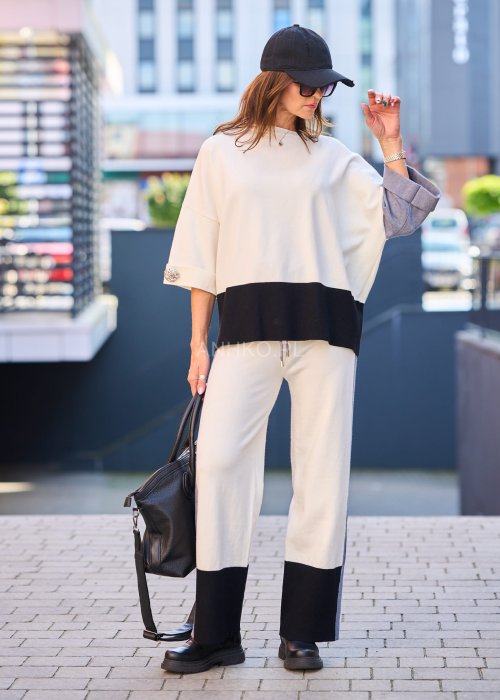 Damski komplet w stylu casual – oversizowa bluzka z szerokimi rękawami w kolorze biało–szaro–czarnym, ozdobiona broszkami przy mankietach, zestawiona z dopasowanymi spodniami w tej samej kolorystyce