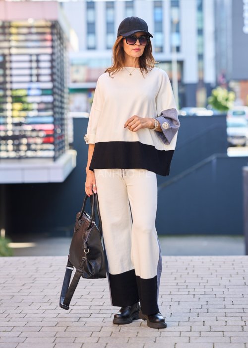 Damski komplet w stylu casual – oversizowa bluzka z szerokimi rękawami w kolorze biało–szaro–czarnym, ozdobiona broszkami przy mankietach, zestawiona z dopasowanymi spodniami w tej samej kolorystyce