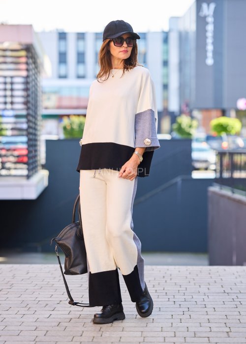 Damski komplet w stylu casual – oversizowa bluzka z szerokimi rękawami w kolorze biało–szaro–czarnym, ozdobiona broszkami przy mankietach, zestawiona z dopasowanymi spodniami w tej samej kolorystyce