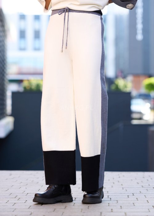 Damski komplet w stylu casual – oversizowa bluzka z szerokimi rękawami w kolorze biało–szaro–czarnym, ozdobiona broszkami przy mankietach, zestawiona z dopasowanymi spodniami w tej samej kolorystyce