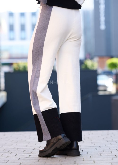 Damski komplet w stylu casual – oversizowa bluzka z szerokimi rękawami w kolorze biało–szaro–czarnym, ozdobiona broszkami przy mankietach, zestawiona z dopasowanymi spodniami w tej samej kolorystyce