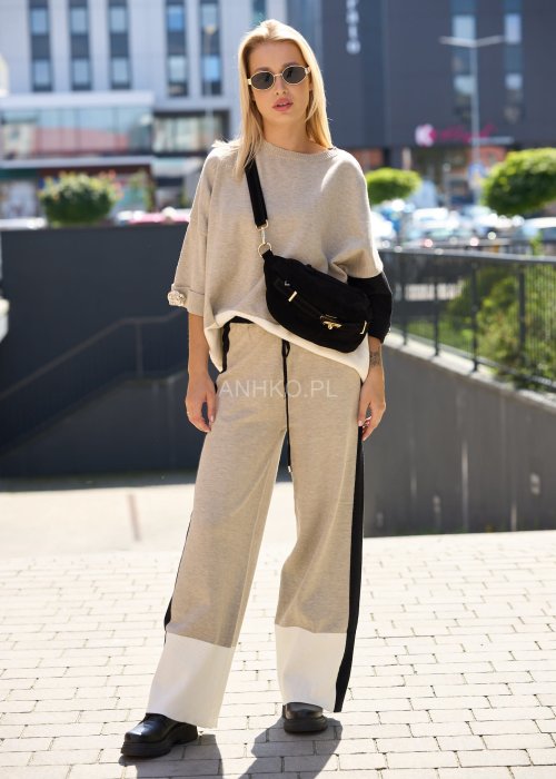 Damski beżowy komplet dresowy – luźna bluza z szerokimi rękawami i kontrastowymi czarnymi wstawkami, zestawiona ze spodniami z szerokimi nogawkami, wykończonymi białymi panelami