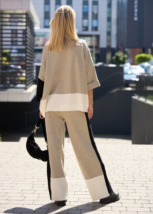 Damski beżowy komplet dresowy – luźna bluza z szerokimi rękawami i kontrastowymi czarnymi wstawkami, zestawiona ze spodniami z szerokimi nogawkami, wykończonymi białymi panelami