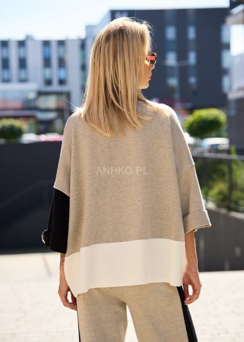 Damski beżowy komplet dresowy – luźna bluza z szerokimi rękawami i kontrastowymi czarnymi wstawkami, zestawiona ze spodniami z szerokimi nogawkami, wykończonymi białymi panelami