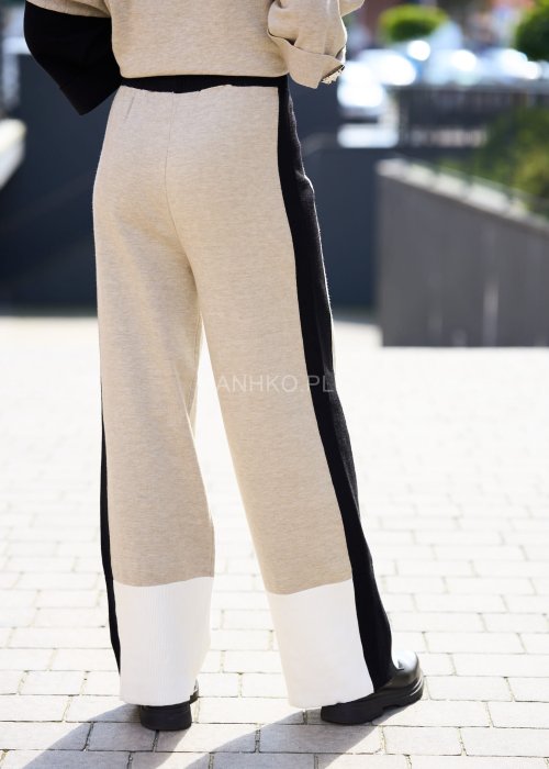 Damski beżowy komplet dresowy – luźna bluza z szerokimi rękawami i kontrastowymi czarnymi wstawkami, zestawiona ze spodniami z szerokimi nogawkami, wykończonymi białymi panelami