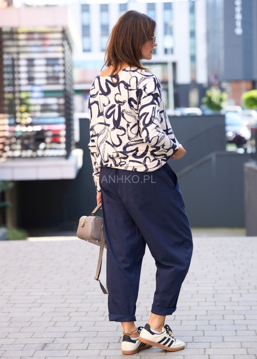 Granatowe spodnie damskie o luźnym kroju boyfriend z elastycznym pasem i troczkiem, pokazane w codziennej stylizacji ze sneakersami. Model ma zwężaną nogawkę, boczne kieszenie i swobodnie układa się na sylwetce.