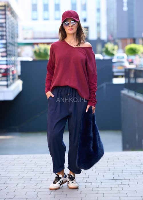 Granatowe spodnie damskie o luźnym kroju boyfriend z elastycznym pasem i troczkiem, pokazane w codziennej stylizacji ze sneakersami. Model ma zwężaną nogawkę, boczne kieszenie i swobodnie układa się na sylwetce.