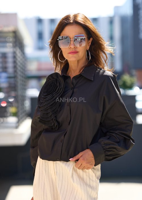 Czarna koszula damska z długim rękawem, ozdobiona dużą plisowaną aplikacją w formie kwiatu, elegancki styl