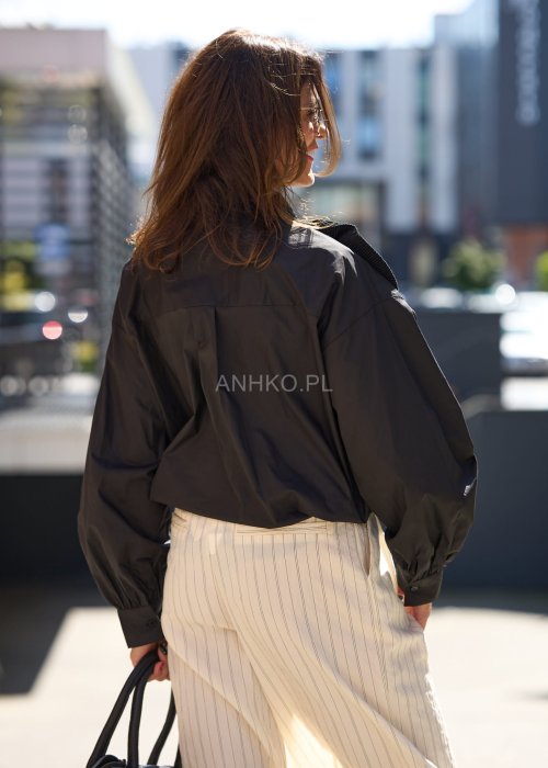 Czarna koszula damska z długim rękawem, ozdobiona dużą plisowaną aplikacją w formie kwiatu, elegancki styl