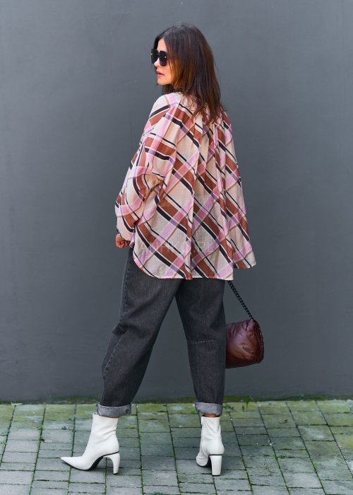 Wzorzysta bluzka w różowo-brązową kratę, kremowe spodnie i brązowy pasek, do tego duże okulary i delikatny naszyjnik.