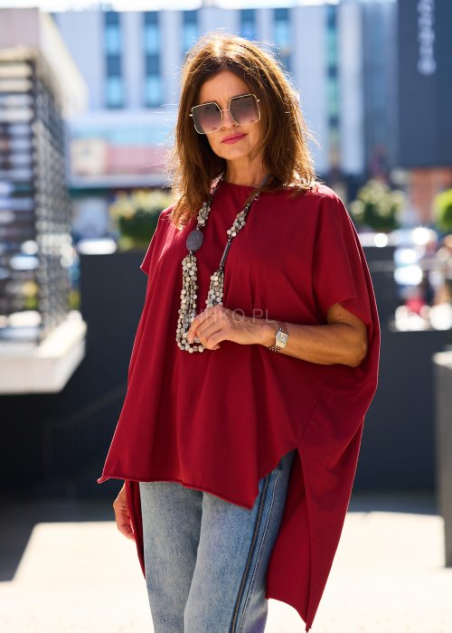 Bordowa bluzka oversize z asymetrycznym dołem i wydłużonym tyłem, zestawiona z jasnymi jeansami. Luźny fason i gładki materiał nadają stylizacji nowoczesny, miejski charakter.