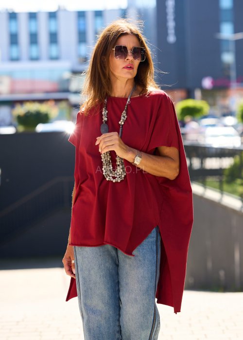 Bordowa bluzka oversize z asymetrycznym dołem i wydłużonym tyłem, zestawiona z jasnymi jeansami. Luźny fason i gładki materiał nadają stylizacji nowoczesny, miejski charakter.