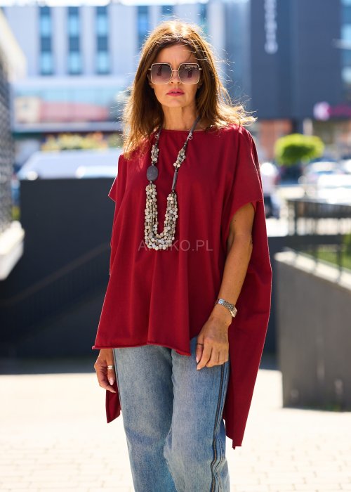 Bordowa bluzka oversize z asymetrycznym dołem i wydłużonym tyłem, zestawiona z jasnymi jeansami. Luźny fason i gładki materiał nadają stylizacji nowoczesny, miejski charakter.