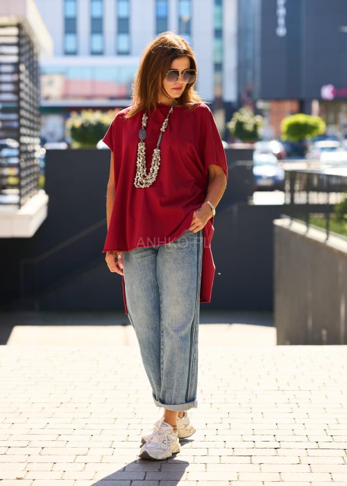 Bordowa bluzka oversize z asymetrycznym dołem i wydłużonym tyłem, zestawiona z jasnymi jeansami. Luźny fason i gładki materiał nadają stylizacji nowoczesny, miejski charakter.