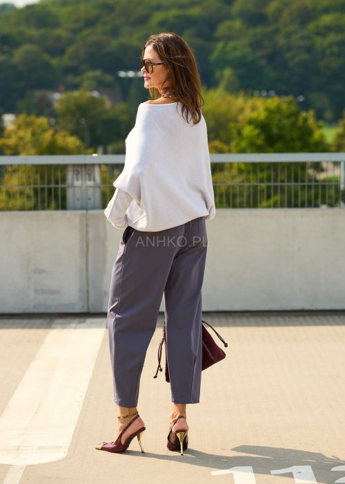 Ciemnoszare spodnie damskie typu cygaretki z elastycznym pasem i zwężaną nogawką, zestawione ze szpilkami w eleganckiej stylizacji miejskiej.