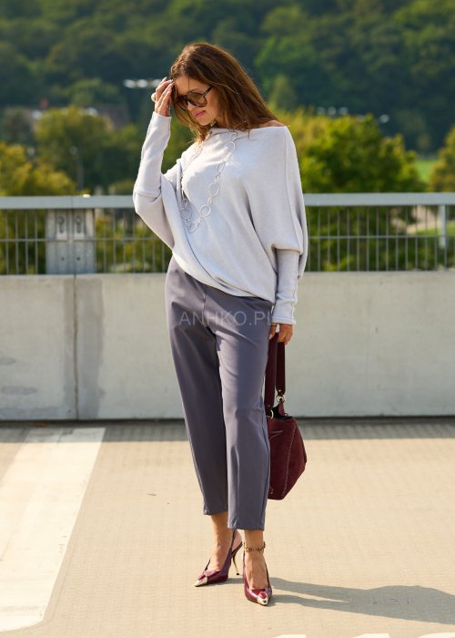 Ciemnoszare spodnie damskie typu cygaretki z elastycznym pasem i zwężaną nogawką, zestawione ze szpilkami w eleganckiej stylizacji miejskiej.