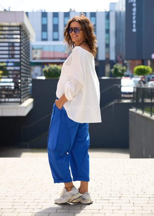 Niebieskie damskie spodnie dresowe o luźnym kroju z ozdobnymi przeszyciami i wiązaniem w pasie. Model z kieszeniami, pokazany w codziennej stylizacji ze sneakersami.