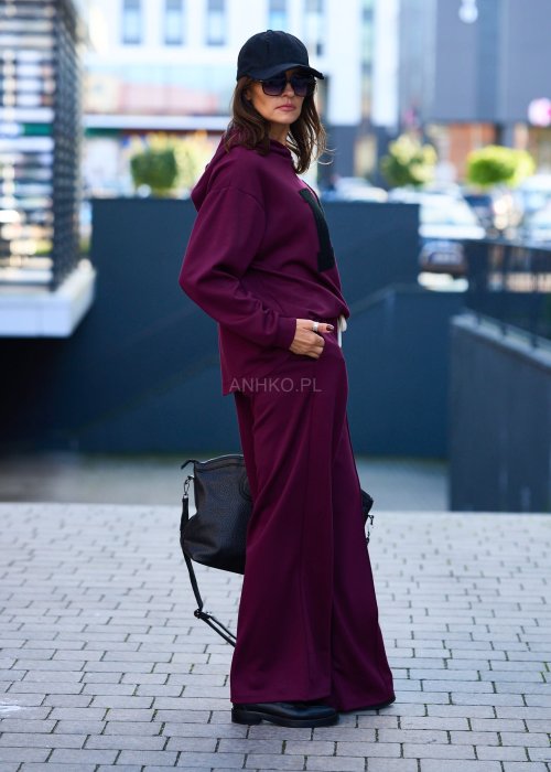 Burgundowy komplet dresowy damski z oversize’ową bluzą z literą M i szerokimi spodniami z elastycznym pasem, stylizacja w miejskim klimacie z czapką z daszkiem.