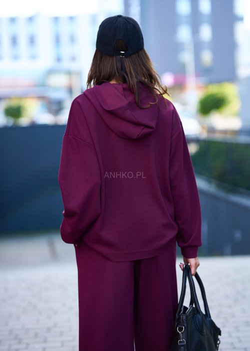 Burgundowy komplet dresowy damski z oversize’ową bluzą z literą M i szerokimi spodniami z elastycznym pasem, stylizacja w miejskim klimacie z czapką z daszkiem.