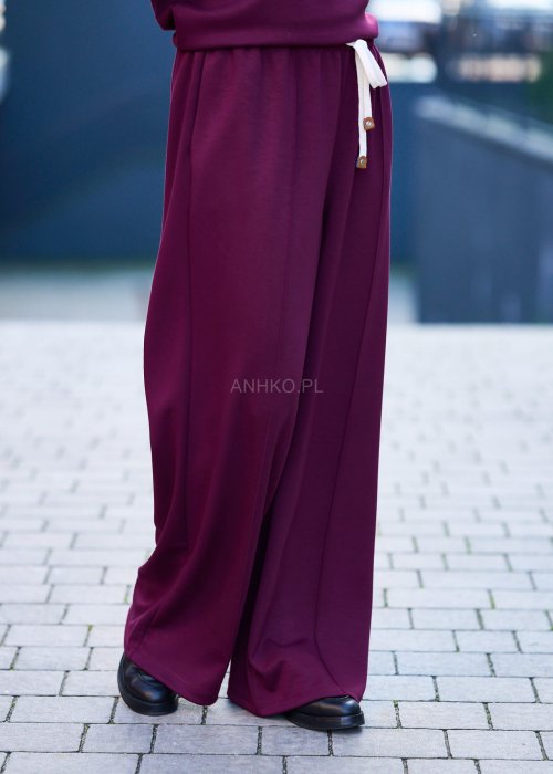 Burgundowy komplet dresowy damski z oversize’ową bluzą z literą M i szerokimi spodniami z elastycznym pasem, stylizacja w miejskim klimacie z czapką z daszkiem.