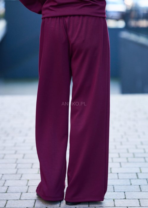 Burgundowy komplet dresowy damski z oversize’ową bluzą z literą M i szerokimi spodniami z elastycznym pasem, stylizacja w miejskim klimacie z czapką z daszkiem.