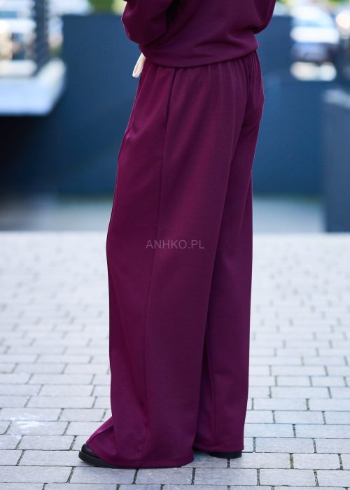 Burgundowy komplet dresowy damski z oversize’ową bluzą z literą M i szerokimi spodniami z elastycznym pasem, stylizacja w miejskim klimacie z czapką z daszkiem.