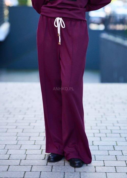 Burgundowy komplet dresowy damski z oversize’ową bluzą z literą M i szerokimi spodniami z elastycznym pasem, stylizacja w miejskim klimacie z czapką z daszkiem.