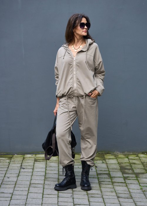 Damski komplet dresowy oversize w kolorze taupe z bluzą na zamek i spodniami z elastycznym pasem, stylizacja miejska z botkami.