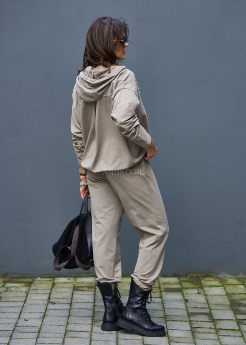 Damski komplet dresowy oversize w kolorze taupe z bluzą na zamek i spodniami z elastycznym pasem, stylizacja miejska z botkami.