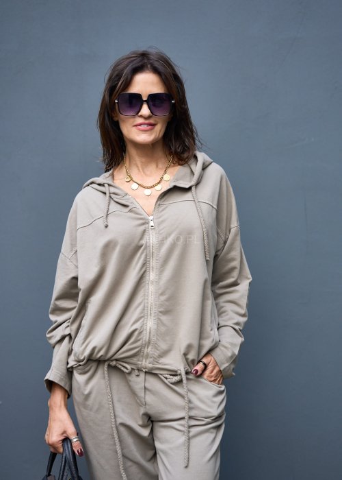 Damski komplet dresowy oversize w kolorze taupe z bluzą na zamek i spodniami z elastycznym pasem, stylizacja miejska z botkami.