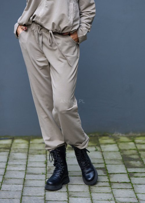 Damski komplet dresowy oversize w kolorze taupe z bluzą na zamek i spodniami z elastycznym pasem, stylizacja miejska z botkami.