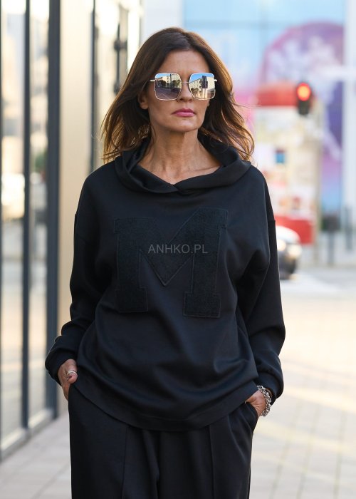 Czarny komplet dresowy damski z oversize’ową bluzą z literą M i szerokimi spodniami z elastycznym pasem, stylizacja w minimalistycznym, miejskim klimacie.