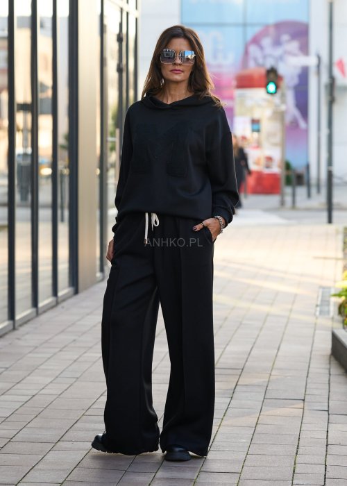 Czarny komplet dresowy damski z oversize’ową bluzą z literą M i szerokimi spodniami z elastycznym pasem, stylizacja w minimalistycznym, miejskim klimacie.