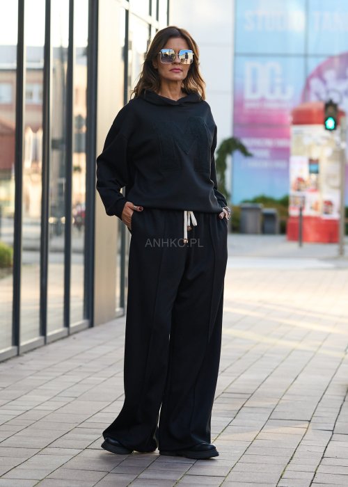 Czarny komplet dresowy damski z oversize’ową bluzą z literą M i szerokimi spodniami z elastycznym pasem, stylizacja w minimalistycznym, miejskim klimacie.