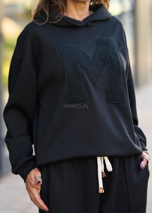 Czarny komplet dresowy damski z oversize’ową bluzą z literą M i szerokimi spodniami z elastycznym pasem, stylizacja w minimalistycznym, miejskim klimacie.